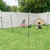 A woman in a garden which chickens inside a fenced off area.