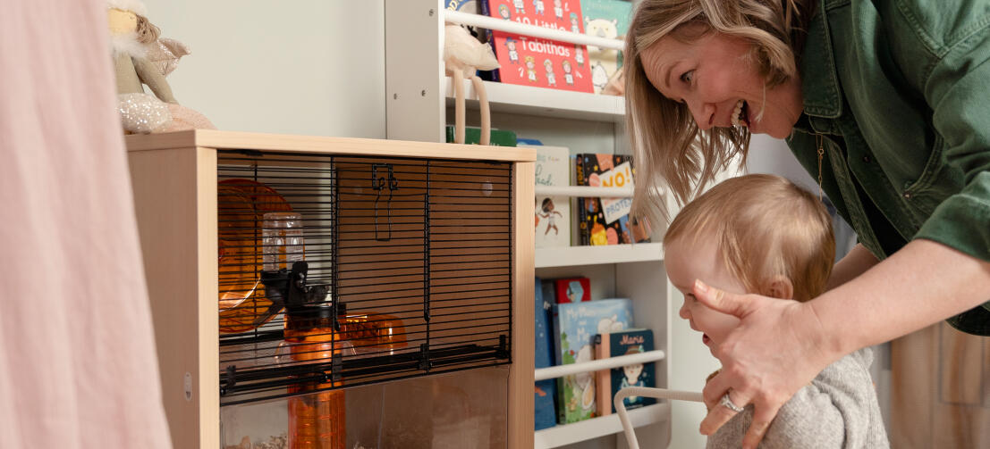 A mother and baby enjoying viewing a hamster in the Qute cage.