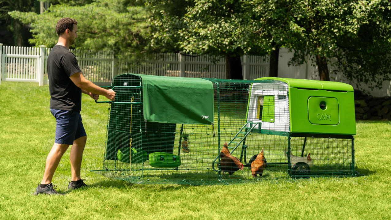 Man moving a a large chicken coop and run easily across the garden