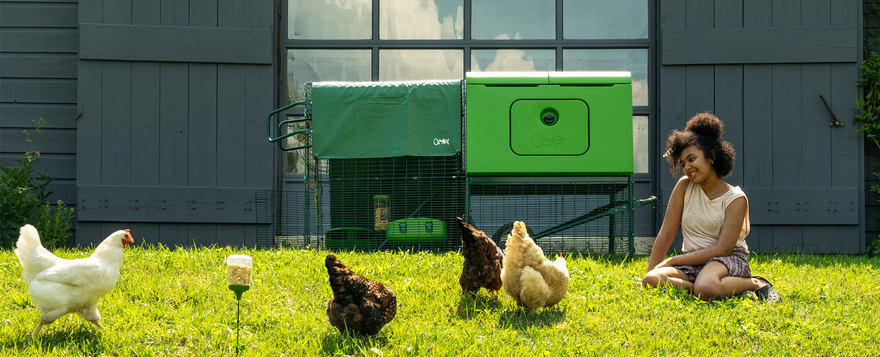 Woman sitting on the grass next to her Eglu Cube large chicken coop