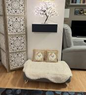 A grey bed with sheepskin topper in a room