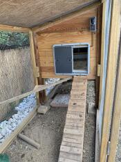 Grey Autodoor on a wooden chicken coop with a ramp