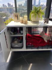 A Fido white dog crate with a wardrobe section and grey dog bed