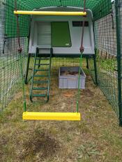 A perch hanging inside an Omlet chicken coop run.