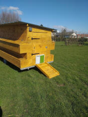 A large wooden chicken coop with an automatic door opener attached.