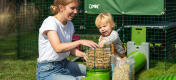 A mother helping her child put hay into the Zippi tunnel hayrack.