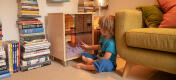 Little boy sitting on the living room floor looking at his pet in the Qute cage.