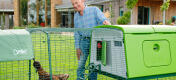 Man with large Eglu chicken coop and run in a garden