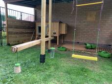Garden setup for chickens with a peck toy, treat caddy chicken swing, grub feeders and a coop with an Autodoor