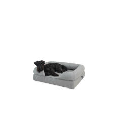 A small black dog lying on a grey memory foam bolster bed