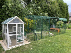 A large run next to a grey and white wooden coop