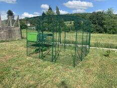A large run connected to a chicken coop in a garden