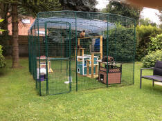 A large walk in run catio setup for cats with toys, cat tress, scratches and accessories inside