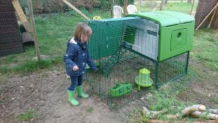 Girl with Omlet green Eglu Cube large chicken coop and run in garden