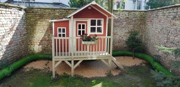 A small play house in a garden with a Zippi tunnel around it