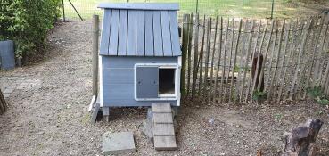 A grey automatic door opening on a wooden chicken coop.