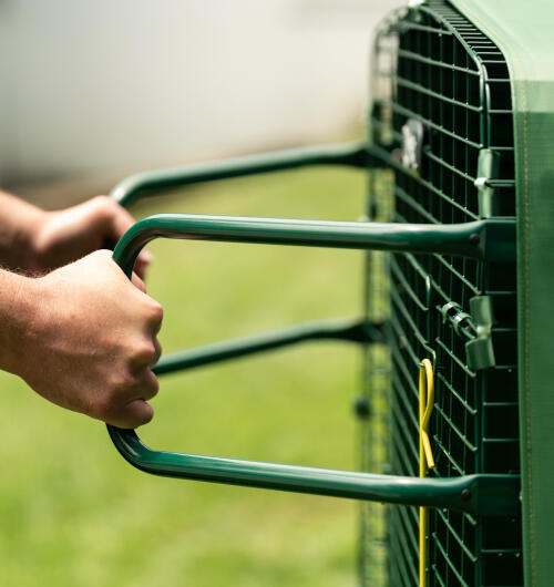 A pair of hands using the Eglu run handles to move the run.