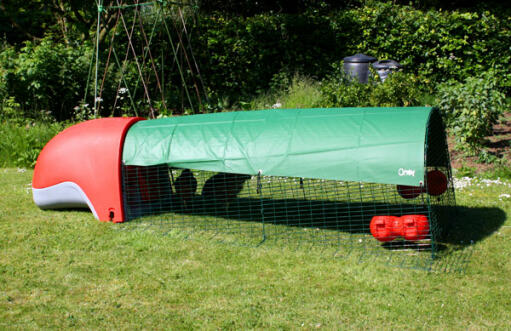 Red Eglu Classic chicken coop with run and full length green cover providing shade in the garden