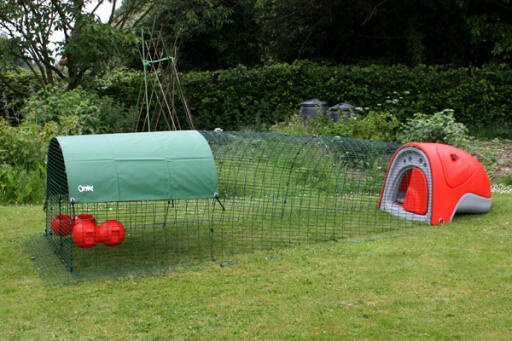 A chicken coop with a cover and feeders and drinker.