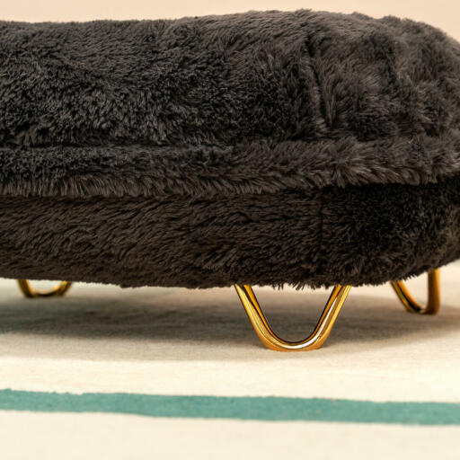 A close up image of the gold hair pin feet on the earl grey donut cat bed