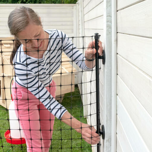 Attaching Omlet chicken fencing to the wall using the wall connectors.