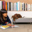 Dog sitting on Omlet Topology dog bed with quilted topper and black rail feet investigating girls book