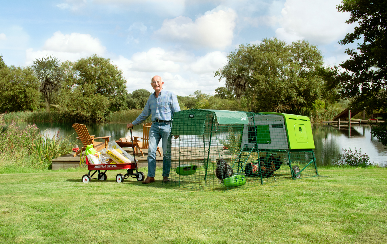 man in a garden with his easy to move chicken coop and radio flyer cart