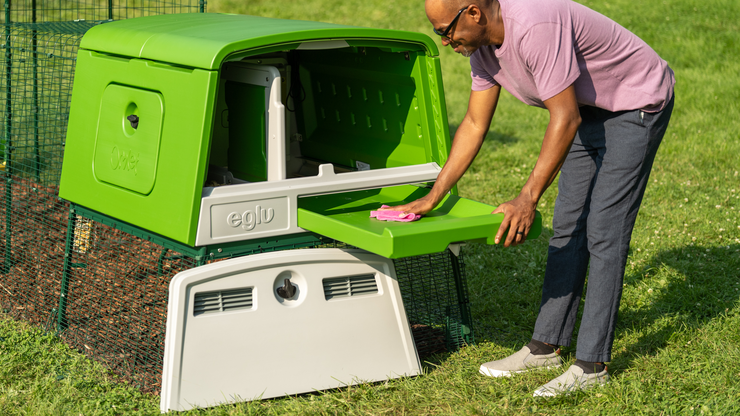 A man cleaning his Eglu Cube chicken coop in a garden