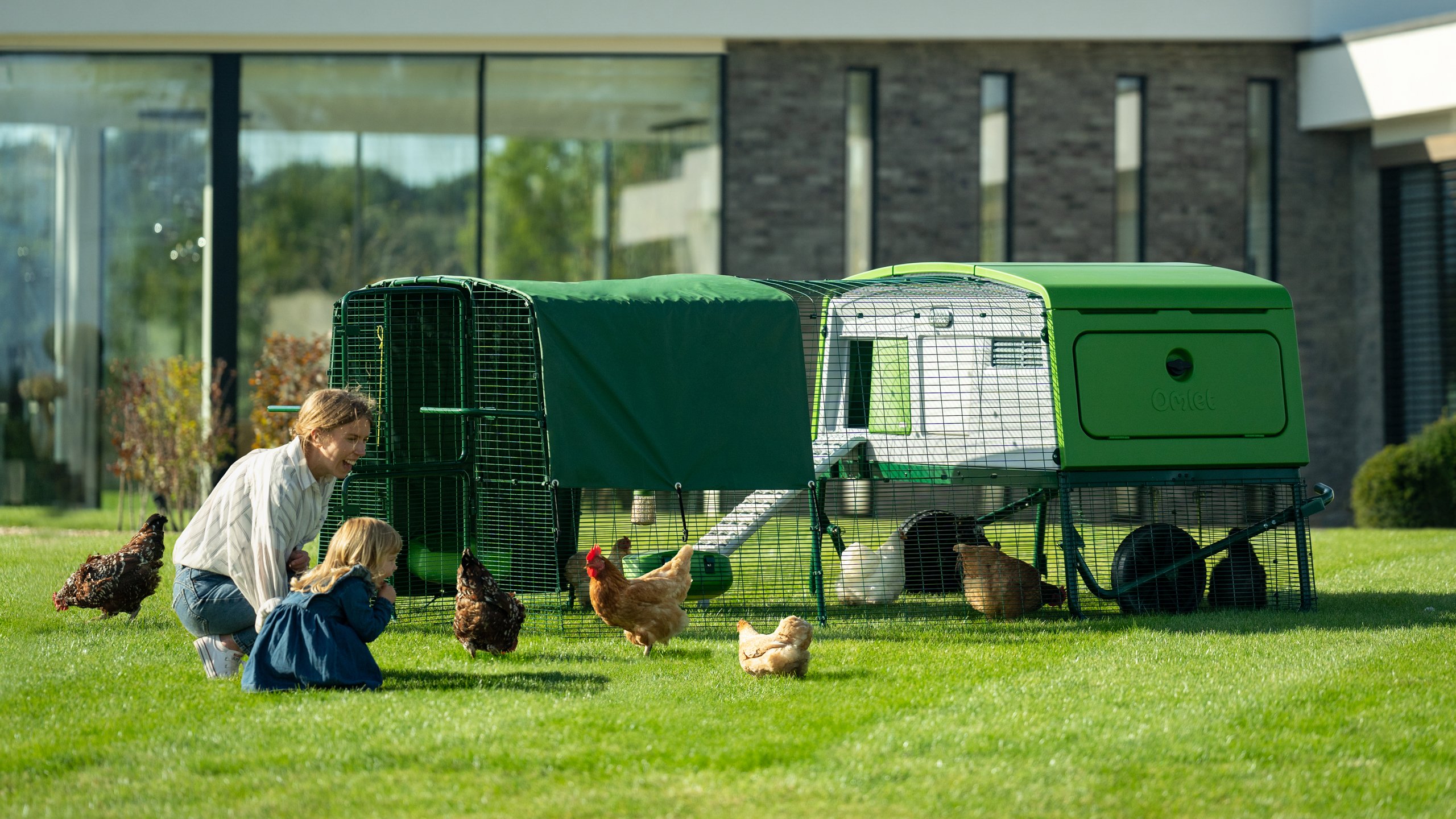 Woman and child crouching next to the Eglu Pro large chicken coop