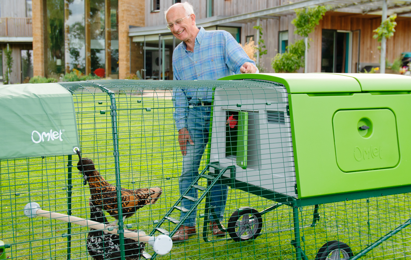 Man stood admiring his chickens inside Eglu Cube chicken coop run.