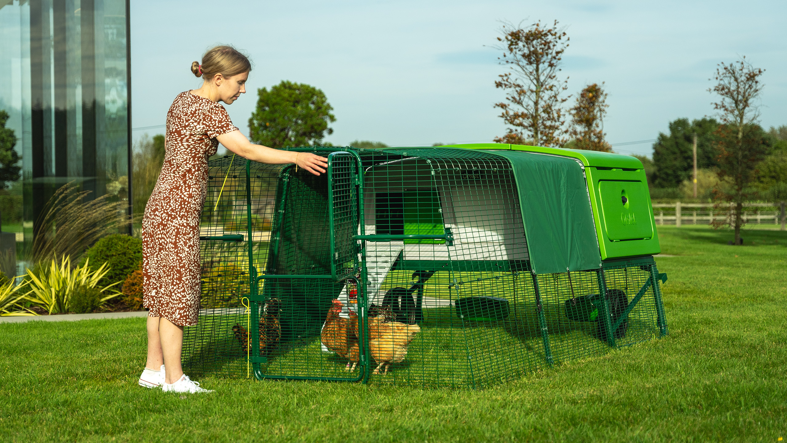 Woman opening the run door on her Eglu Pro chicken coop.