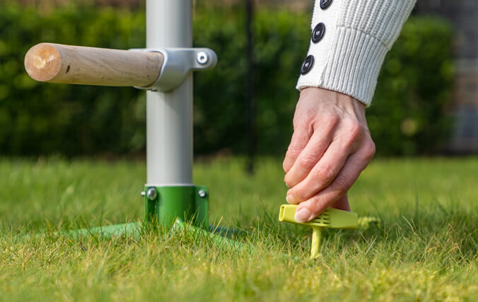 Woman securing the free standing chicken perch into your lawn with easy to use screw pegs