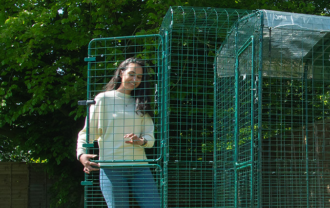 Woman entering a cat walk in run using the omlet catio porch